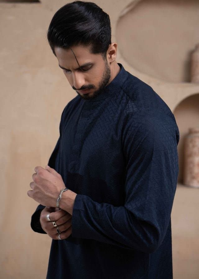 Close crop of a model fastening the cuff of a navy kurta